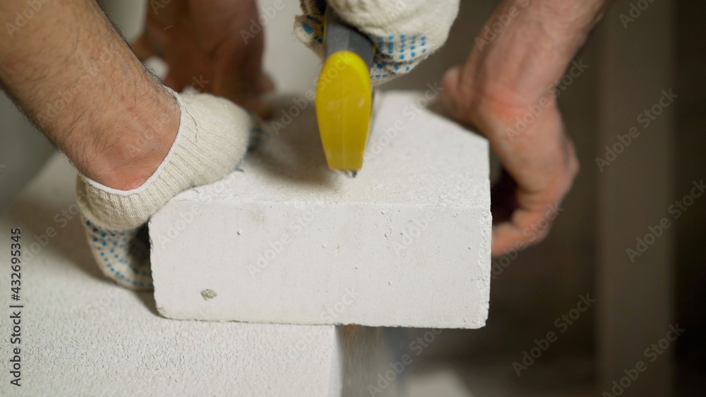 Worker cutting construction blocks made from aerated concrete using handsaw. A worker cuts an aerated concrete block.